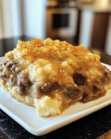 Hearty One Pot Cheeseburger Macaroni with melted cheddar, tender beef, and garnished pickles.